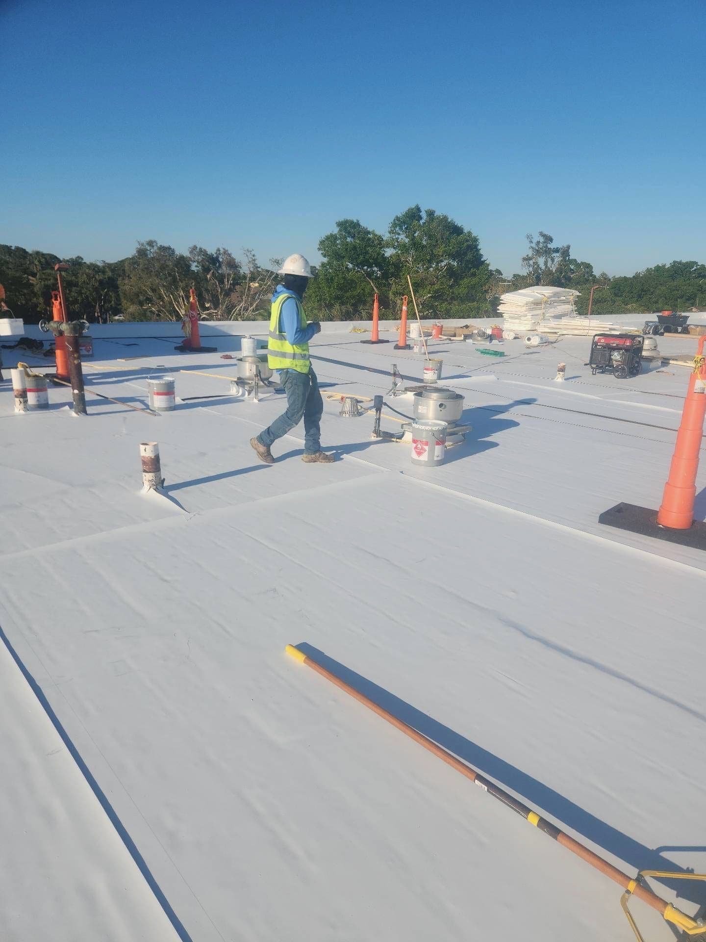 Worker walking across a freshly installed white TPO commercial roof membrane