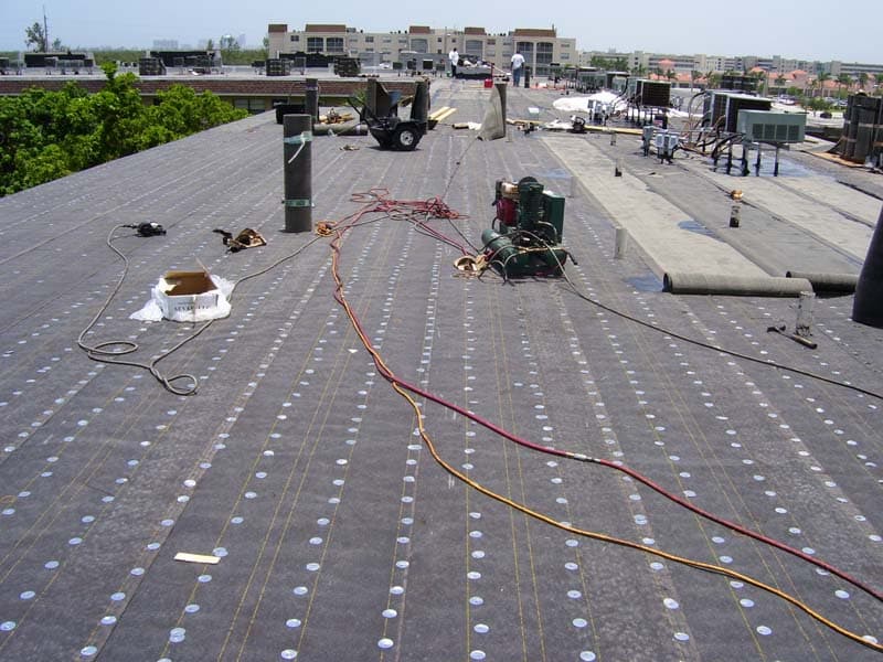 Aerial view of a modified bitumen commercial roof with fastening equipment and cabling laid out