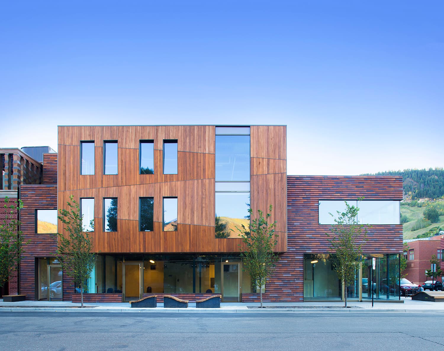 Modern commercial building with wood-clad facade and street-level storefronts