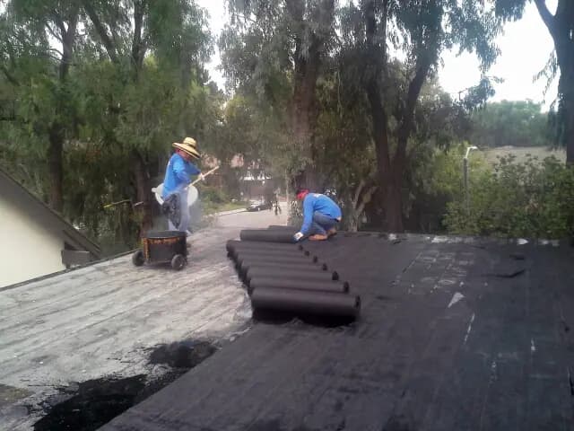 Crew torch-applying modified bitumen roofing on a flat roof