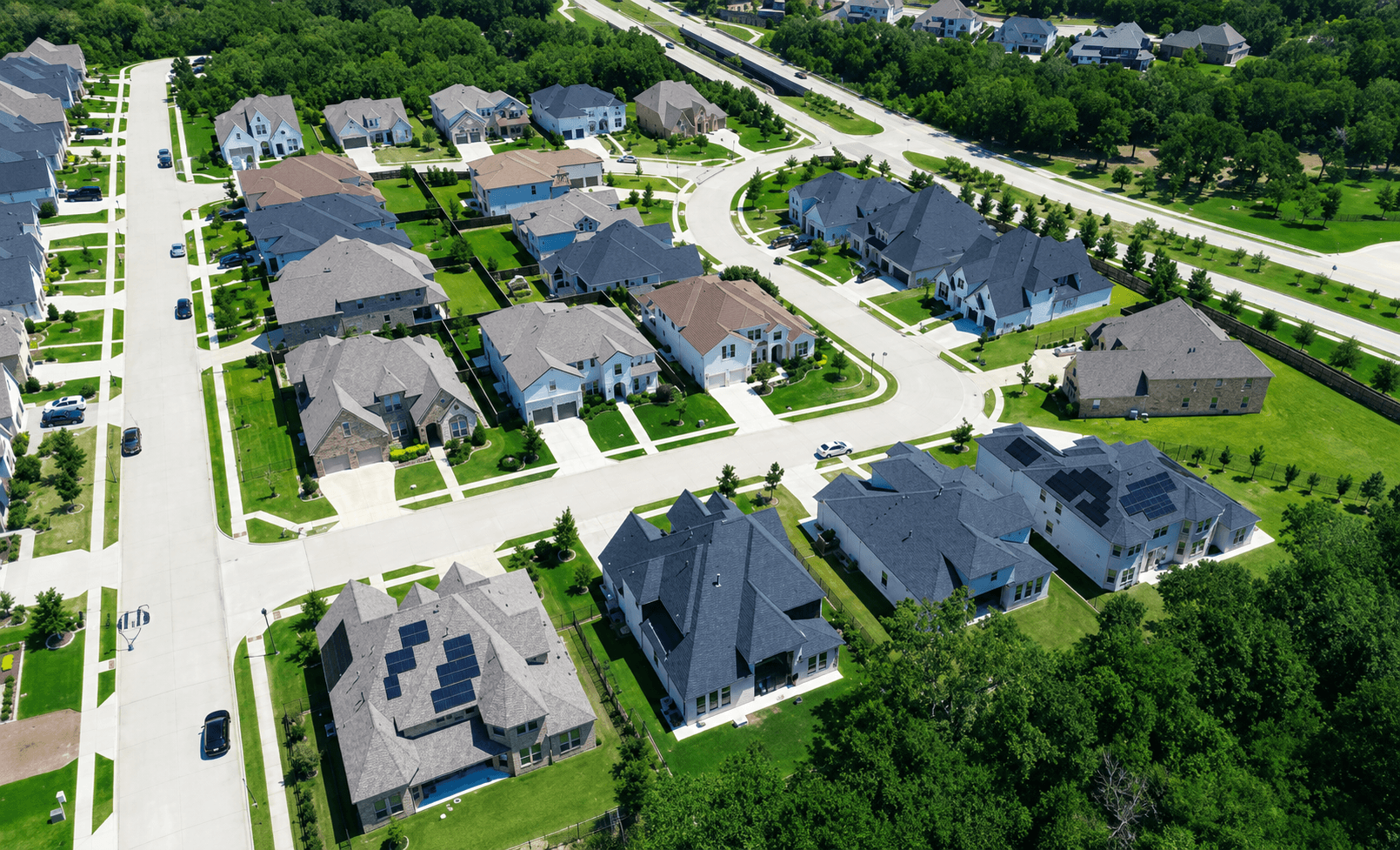 Aerial view of a suburban HOA community with curved streets and matching shingle roofs