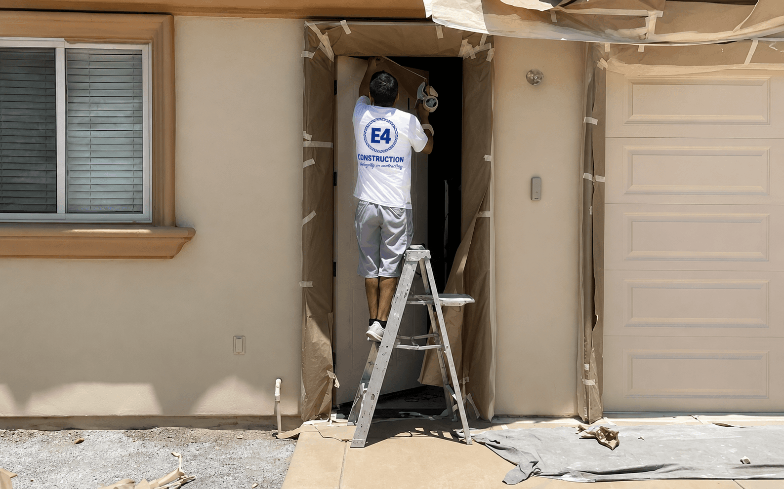 E4 crew member masking and taping a doorway before painting
