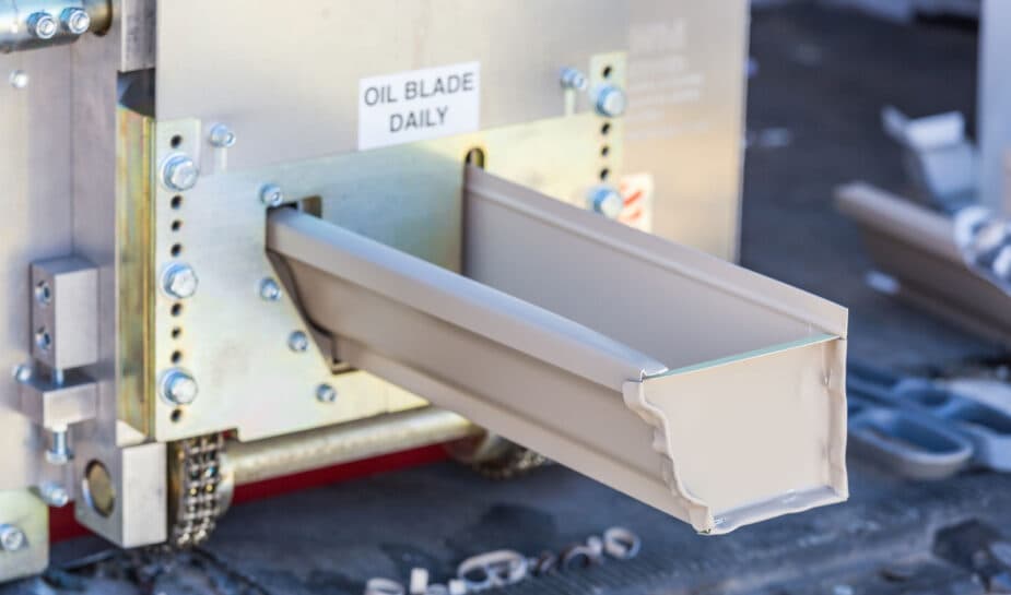 A fresh seamless gutter length coming off the on-site forming machine