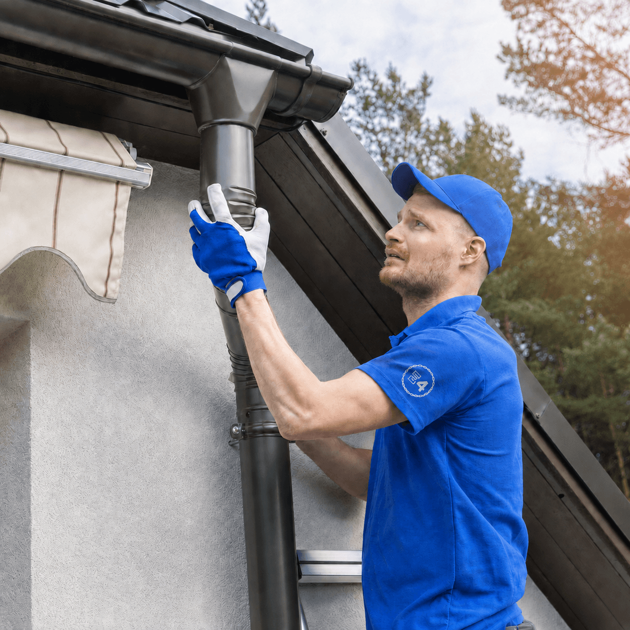 Close-up of an E4 crew member securing a gutter downspout to the fascia