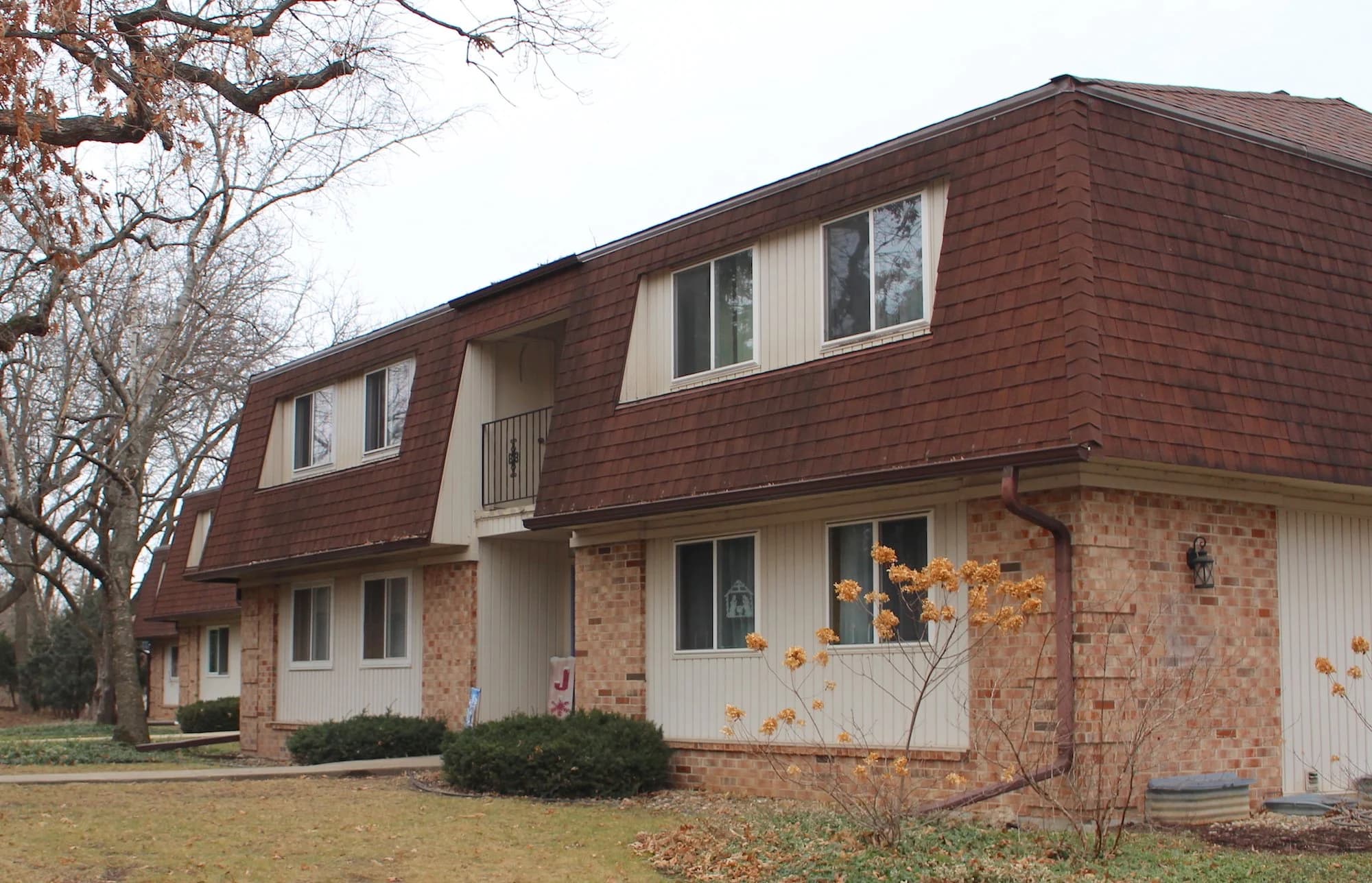 Brick and shingle townhome community exterior with dormer windows