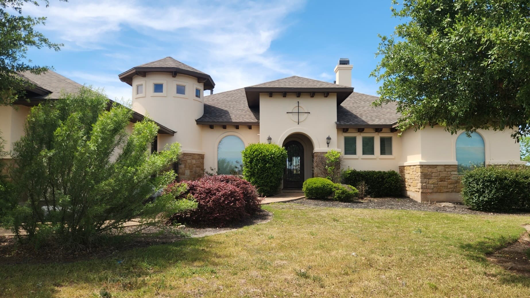 Mediterranean-style stucco home with a dimensional shingle roof and turret