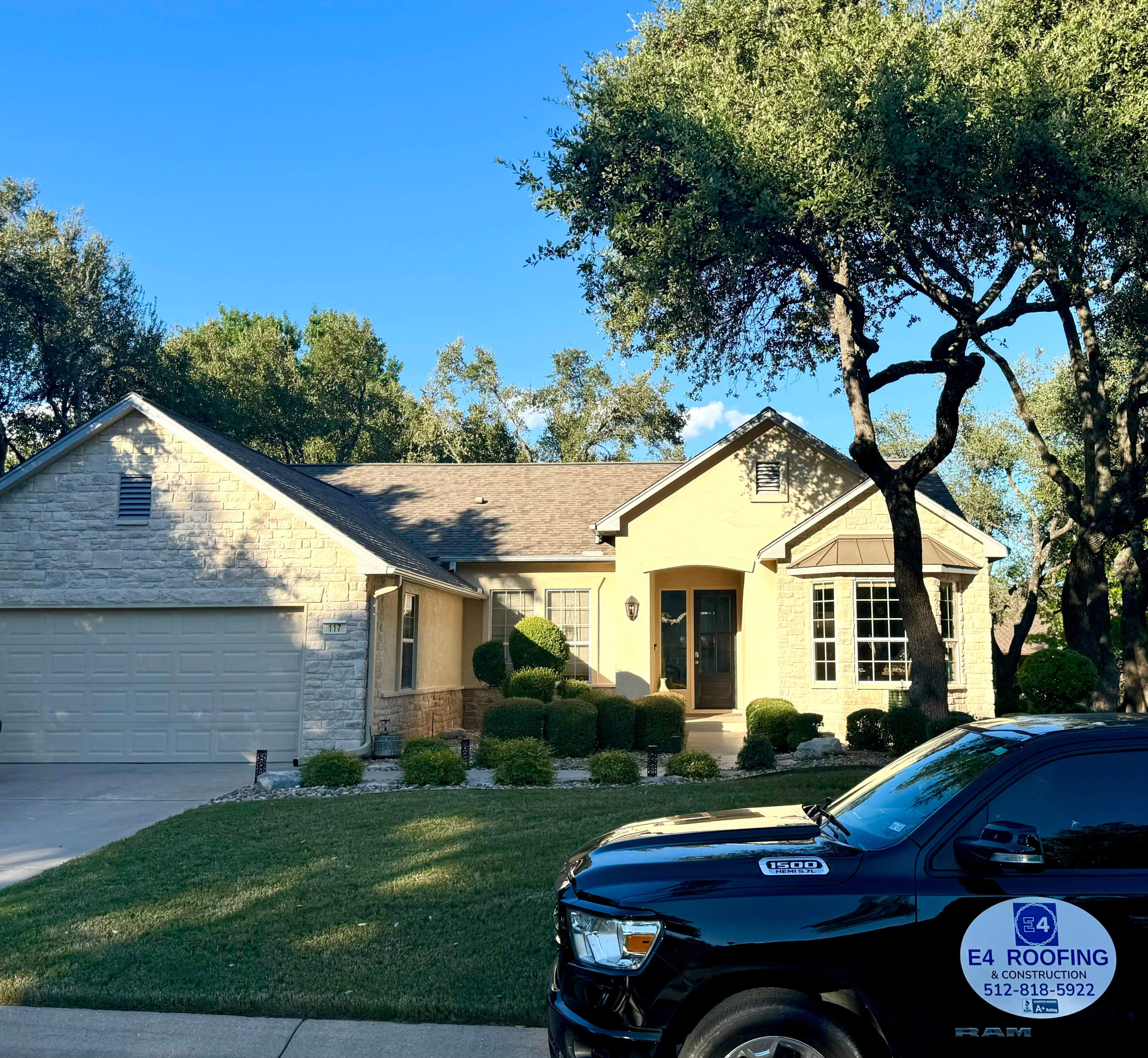 Completed shingle roof installation with the E4 Construction truck parked in the driveway