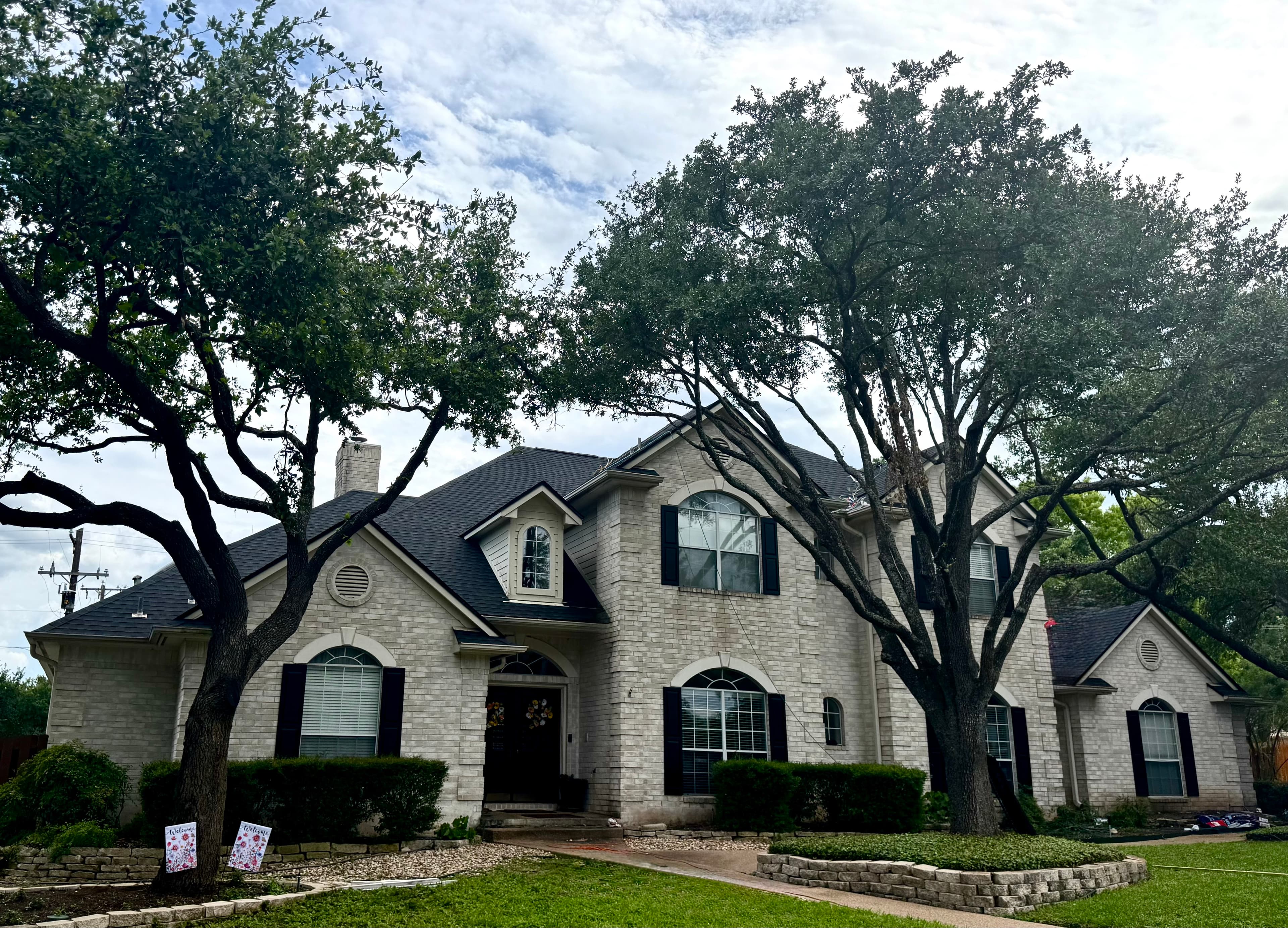 Two-story brick and stone home with a dark architectural shingle roof