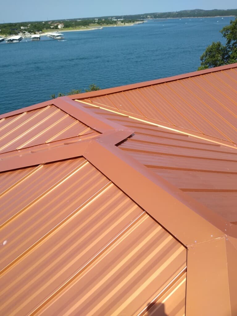 Close-up of a copper-tone standing seam metal roof overlooking a lake