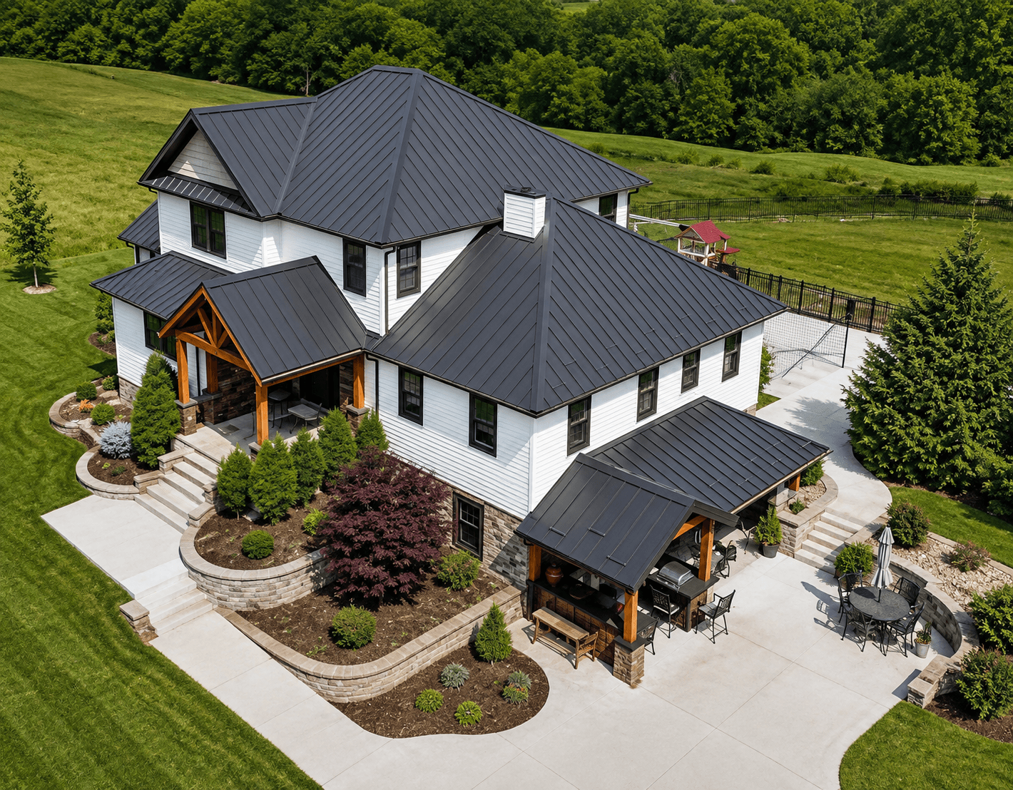Large home with a dark grey standing seam metal roof and covered outdoor living area