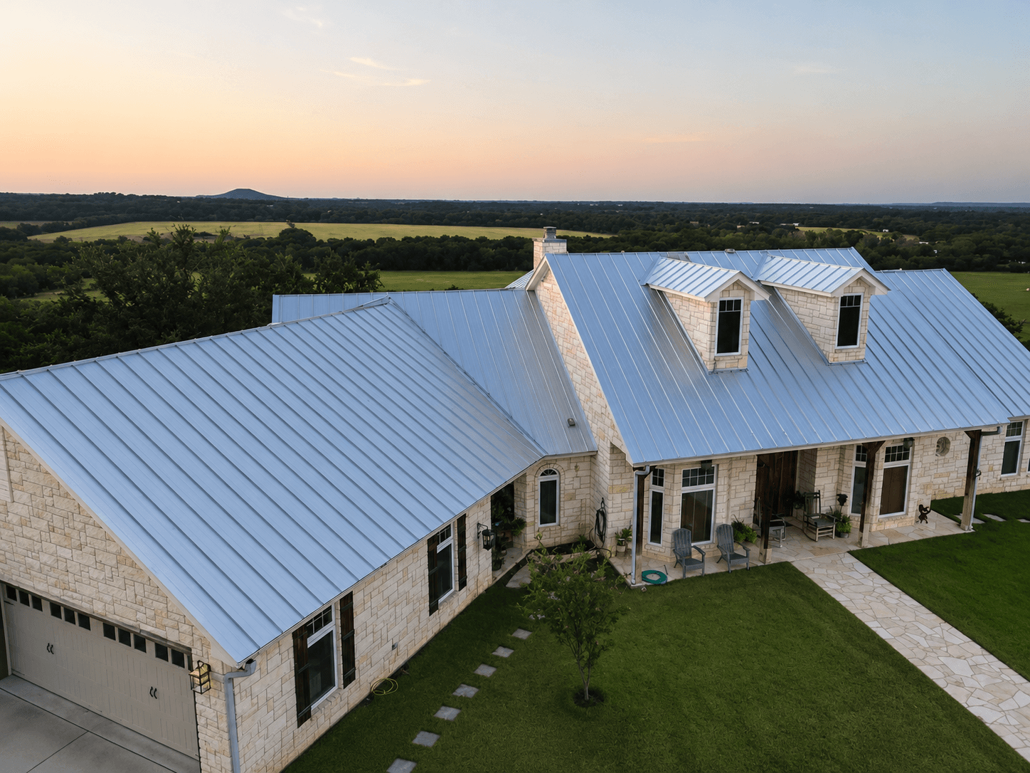 Aerial view of a finished light blue standing seam metal roof at sunset