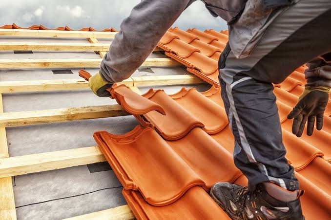 Close-up of a roofer setting clay tiles over underlayment and battens